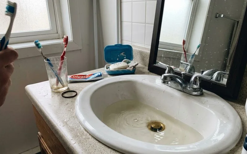 Slow-draining bathroom sink with standing water in daylight